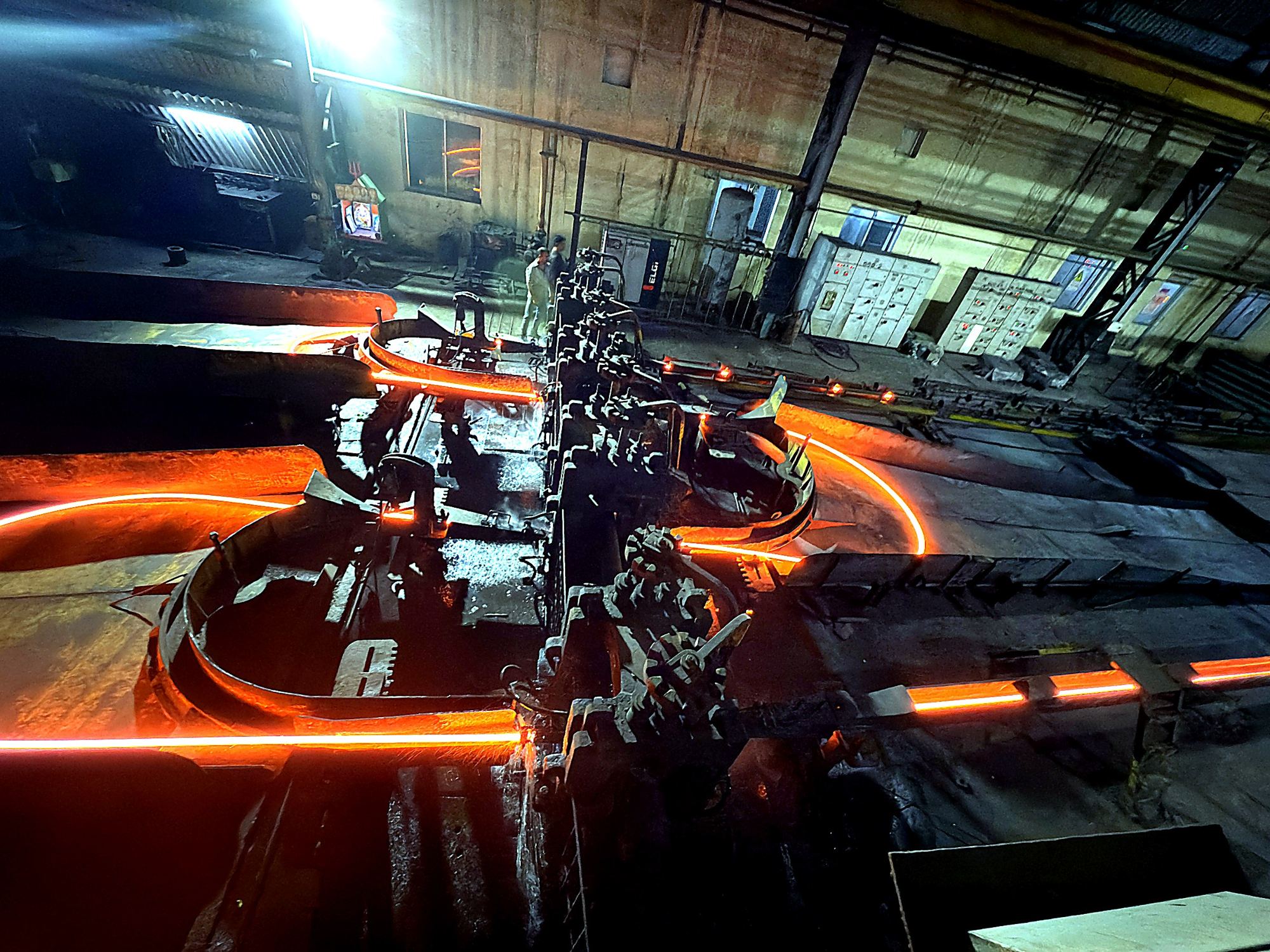 Glowing bars looping through the rolling mill stands
